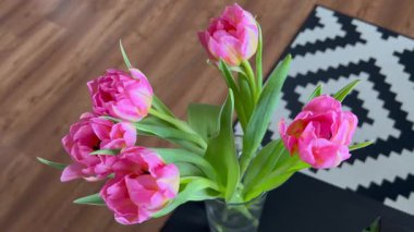 Evdeki pembe laleleri kapat. Siyah masanın üzerinde parlak, yoğun laleler var.. 