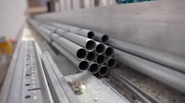İçeriye yerleştirilmiş alüminyum boruların yakın çekimi. İnşaat veya endüstriyel atölyede yakalanmış. Metal profiller kullanıma hazır.