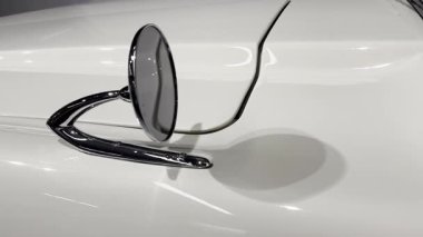 Dikiz aynası eski bir arabanın çamurluğuna monte edilmiş. Bağın zarif eğrisi, pürüzsüz beyaz gövde ve parlak krom bitirme retro tasarımı vurguluyor. 