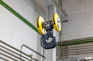 Arka plandaki ışıkla aydınlatılmış asılı duran bir vincin kancası.