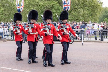 Londra, İngiltere - Mayıs 2023: Klasik kırmızı paltolu ve kürklü askerler Buckingham Palac yakınlarındaki geleneksel Nöbetçi Değişimi töreninde Kraliyet Muhafızları Geçidi boyunca yürüdüler