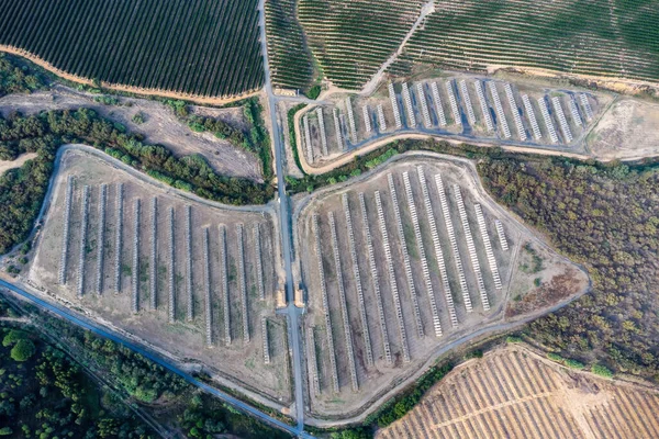Aerial drone view of a farm of solar panels between crop fields