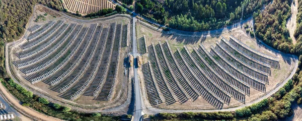 Aerial panoramic drone view of a farm of solar panels between crop fields