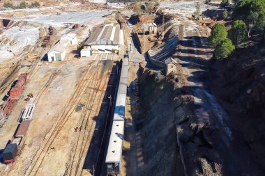Huelva 'nın Minas de Riotinto kasabasında bulunan Corta Atalaya adlı bakır madeni sömürüsünün kalıntılarını gezerken eski turist treninin hava aracı görüntüsü.