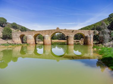 Aerial drone view of roman bridge in the hiking route of the water mills along the Odiel river from Sotiel Coronada, in Huelva province, Andalusia, Spain clipart
