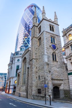 Londra, İngiltere - 20 Mayıs 2023: St Andrew Undershaft Kilisesi, Londra 'da günbatımında, ve The Gherkin, resmi olarak 30 St Mary Axe ve daha önce İsviçre Re Binası olarak bilinen cam gökdelen