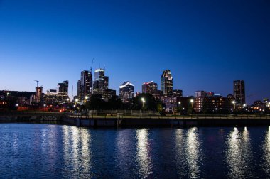 Montreal 'in gece gökyüzü silueti, derin mavi gökyüzünün altında yansıyan bir ışık senfonisi, şehir zarafetini özetliyor..