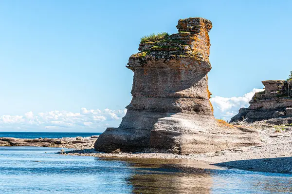 Bitki tacıyla süslenmiş kireçtaşı yığını Niapiskau Adası 'nda Mingan' ın huzur veren güzelliğini yansıtan doğal bir anıt olarak duruyor. 