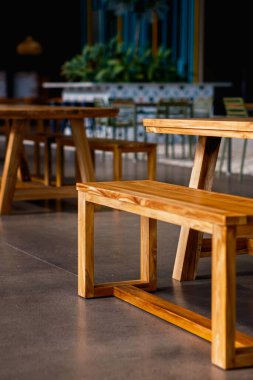 Modern bir kafeteryada veya lokantada, modern ahşap banklar ve masalar. Sıcak ahşap tonlar, parlak beton zeminlerle tezat oluşturarak cezbedici, minimalist bir iç mekan yaratır..