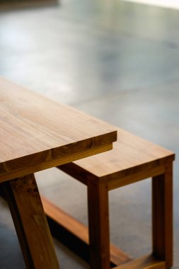 Modern bir ahşap masa ve bankın köşesinin soyut görüntüsü. Sıcak tonlarda ve ahşap tanecikleri vurgulanarak, minimalist iç dekorda işçilik ve dokuyu gösteriyor..