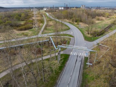 Kohtla-Jarve, Estonya - 20 Nisan 2025: Kohtla-Jrve kentinin endüstriyel kısmının havadan görünüşü. Boş viraj yolları, endüstriyel boru hatları ve ilkbahar başları manzarası. 