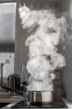 Mutfaktaki tozlu elektrikli ocağın üstünde buharla kaynar su..