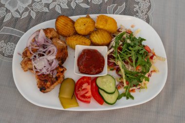 Domates soslu ızgara tavuk, fırında patates ve beyaz tabakta taze sebze. Sağlıklı öğle yemeği.