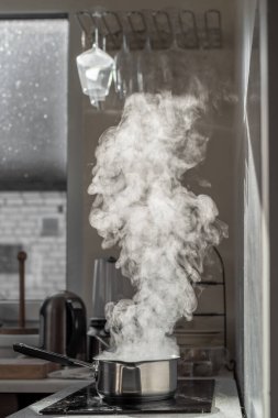 Mutfaktaki tozlu elektrikli ocağın üstünde buharla kaynar su..