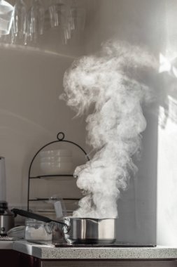 Mutfaktaki tozlu elektrikli ocağın üstünde buharla kaynar su..
