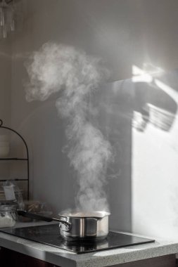 Mutfaktaki tozlu elektrikli ocağın üstünde buharla kaynar su..