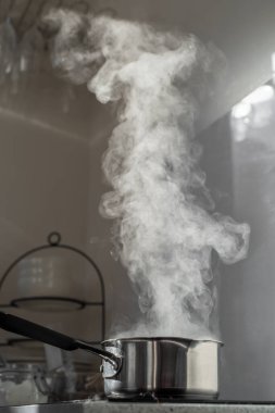 Mutfaktaki tozlu elektrikli ocağın üstünde buharla kaynar su..