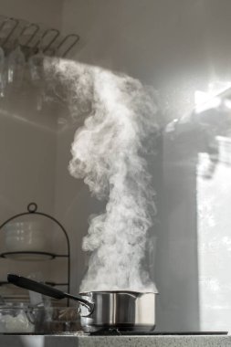 Mutfaktaki tozlu elektrikli ocağın üstünde buharla kaynar su..