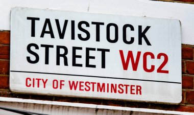 Londra 'nın Westminster şehrindeki Tavistock Sokağı tabelasına yakın çekim. Beyaz arkaplanda kırmızı ve siyah metin özellikleri.