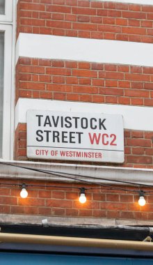 Londra 'nın Westminster şehrinde Tavistock Sokağı için bir tabela. İşaret kırmızı tuğla bir duvara asılmış..