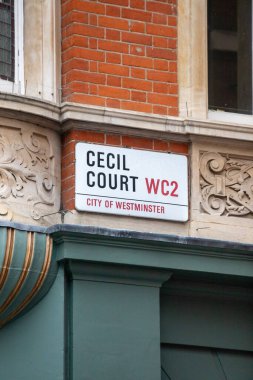 Westminster, Londra 'da bulunan süslü tuğla bina cephesindeki Cecil Court sokak tabelasının yakın çekimi..