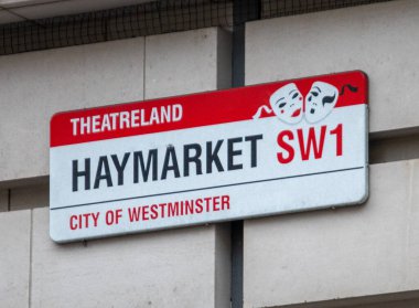 Haymarket için sokak tabelası, Londons Tiyatrosu, Westminster 'da. Tabelada, sembolik tiyatrolara yakınlığını sembolize eden tiyatro maskeleri yer alıyor..
