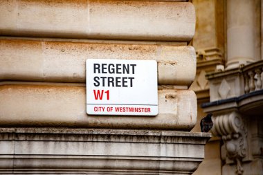 Londra 'nın Westminster şehrindeki Regent Sokağı tabelasına yakın çekim. Yakınlarda bir güvercin tünemiş, kentsel hayat katıyor..