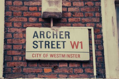 Archer Caddesi 'ndeki tabelayı Westminster, Londra' daki tuğladan bir duvara yakın çekim..