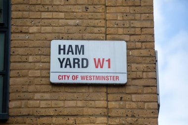 Londra, Westminster 'da Ham Yard W1' i gösteren bir tabela. Tabela tuğla bir duvara asılmış..
