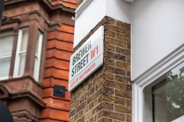 Londra 'nın Westminster şehrindeki Brewer Caddesi tabelasında bir tuğla duvar var. Arkaplan, kırmızı tuğlalı bir binanın parçalarını gösteriyor.