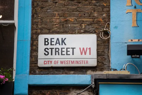 Londra, Westminster 'daki tuğla bir duvara Gaga Sokağı tabelasının yakın çekimi. Tabela kentsel detaylarla çevrili. Kablolar ve renkli boyalar da dahil..