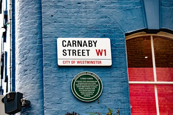 Westminster, Londra 'daki Carnaby Caddesi' ndeki sokak tabelası. Mavi tuğla duvar ikonik konumları canlandırır..