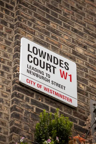 Londra, Westminster 'daki Lowndes Court' ta bir sokak tabelasına yakın çekim. Tuğla duvar ve yeşillik doku ekler.