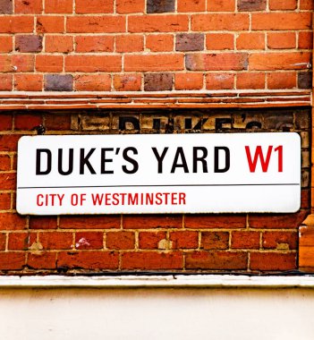Londra, Westminster 'daki Dukes Yard' ın sokak tabelası. Tabela tuğla bir duvara asılmış..