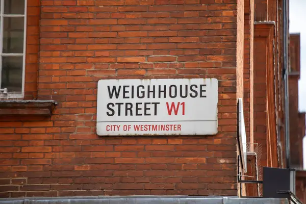 Londra 'nın Westminster şehrindeki Weighhouse Sokağı' nın sokak tabelası. İşaret kırmızı tuğla bir duvara asılmış..