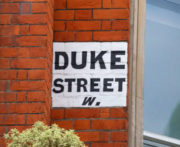 Londra 'da kırmızı tuğlalı bir duvarda Duke Sokağı tabelası var. Tabela beyaz arkaplanda koyu siyah harfler içeriyor..