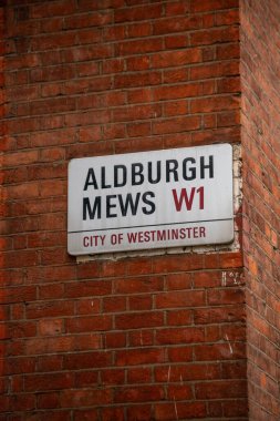 Londra 'nın Westminster şehrinde Aldburgh Mews sokak tabelası. İşaret kırmızı tuğla bir duvara asılmış..
