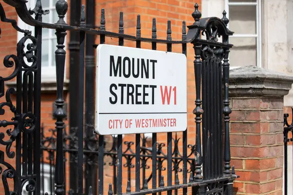 Londra 'nın Westminster şehrindeki Mount Street W1 için sokak tabelası. Tuğla bina zeminine karşı demirden kapılar süslüyor.