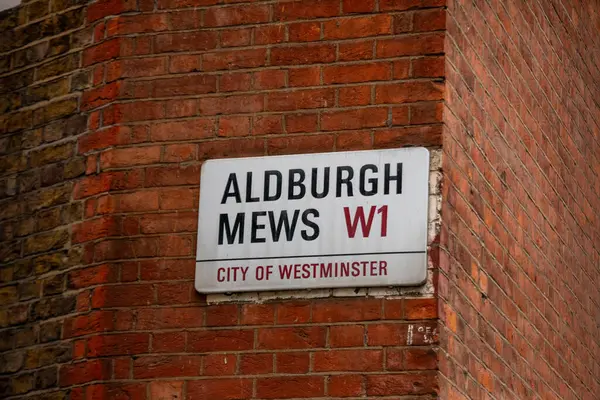 Londra 'nın Westminster şehrindeki Aldburgh Mews için bir sokak tabelası, bir tuğla duvar köşesinde sergileniyor..