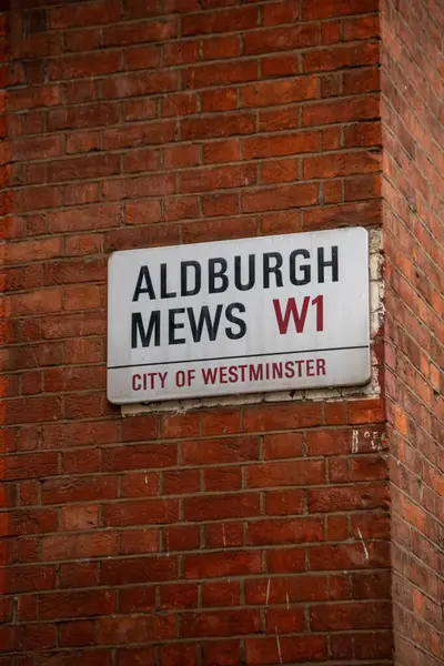 Londra 'nın Westminster şehrinde Aldburgh Mews sokak tabelası. İşaret kırmızı tuğla bir duvara asılmış..