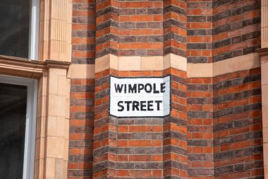Londra 'da bir tuğla binanın üzerindeki Wimpole Sokağı tabelasına yakın çekim. İşaret kırmızı tuğlaya karşı belirgin bir şekilde sergileniyor..