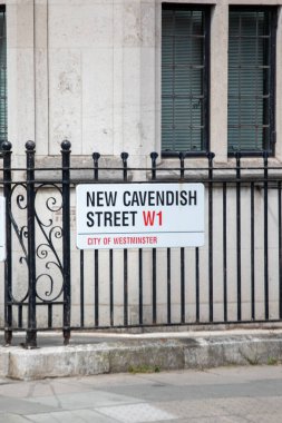 Westminster, Londra 'daki New Cavendish Caddesi için bir tabela. Görüntüde siyah demir parmaklıklar ve tarihi bir bina cephesi yer alıyor..