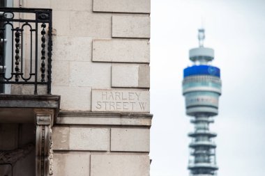 Harley Caddesi 'ndeki sokak tabelasında arka planda BT Kulesi var, Londra..