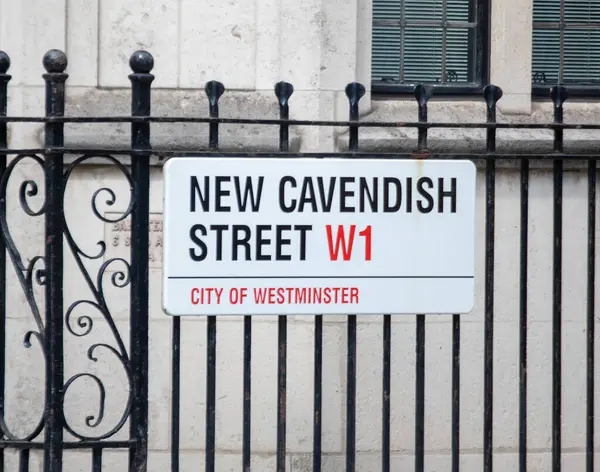 Londra 'nın Westminster şehrindeki New Cavendish Caddesi için bir sokak tabelası. Süslü, siyah bir demir çitte sergileniyor..