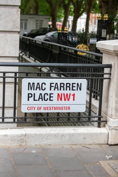 Londra 'nın Westminster şehrinde Mac Farren Place için bir sokak tabelası görüldü. Bölgede park halindeki arabalar ve klasik bir demir çit bulunuyor..