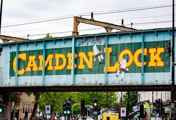 Londra 'da canlı harflerle yazılmış ikonik Camden Lock köprüsü. Aşağıdaki kalabalık sokak sahnesinde insanlar ve trafik.