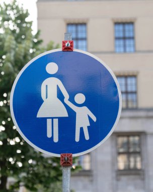 Üzerinde bir bisiklet illüstrasyonunun olduğu mavi bir trafik levhası, yanında açık bir şekilde 