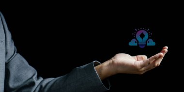 İş adamı elinde parlak bir ampul tutuyor. Fikir ikonu koyu arka planda. Yenilik kavramı.