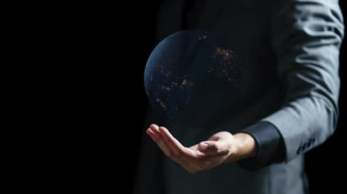 Dünya gezegenini karanlık arka planda gösteren iş adamının eli. Bu görüntünün elementleri Nasa tarafından desteklenmektedir