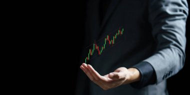 Karanlık bir arkaplanda bir grafik tutan işadamı eli.